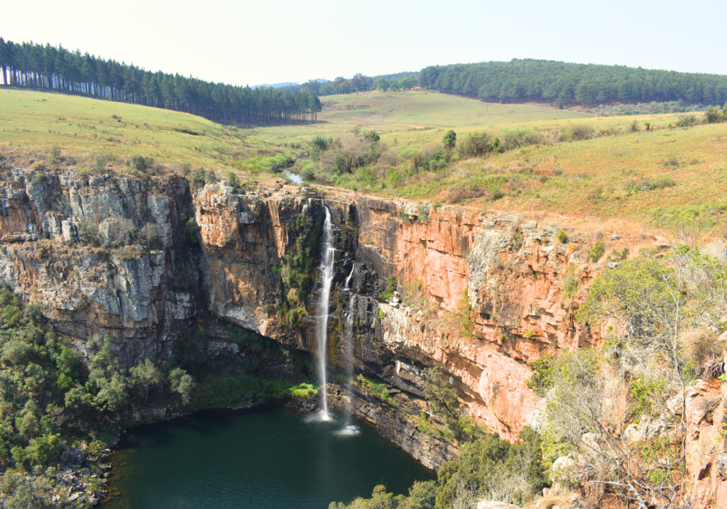 Paysage montrant les différentes couches géologiques rocheuses dans laquelle se jette un cours d'eau formant une cascade et un lac en dessous